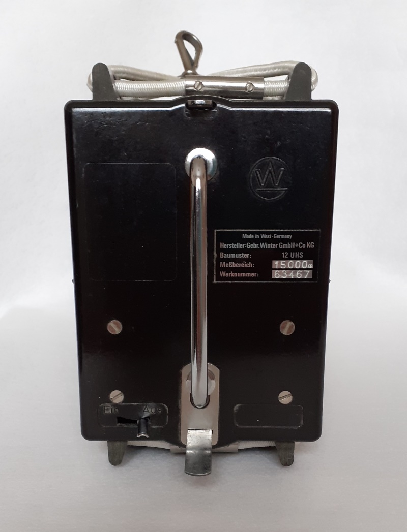 Rear view showing a central chrome handle almost the full height, a plate with manufacturer and construction number. A thick elasticated cord on the top is used to secure it in place. A W is stamped top right.