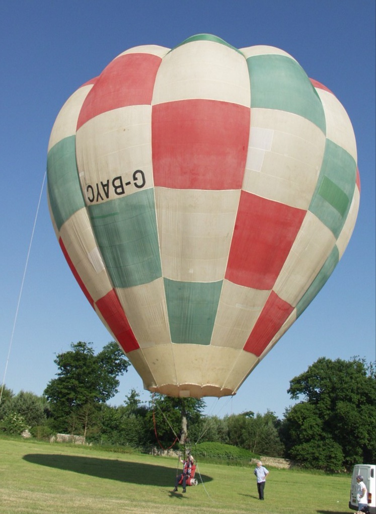 Green, white and red check balloon on the ground inflated. The registration is upside down. 