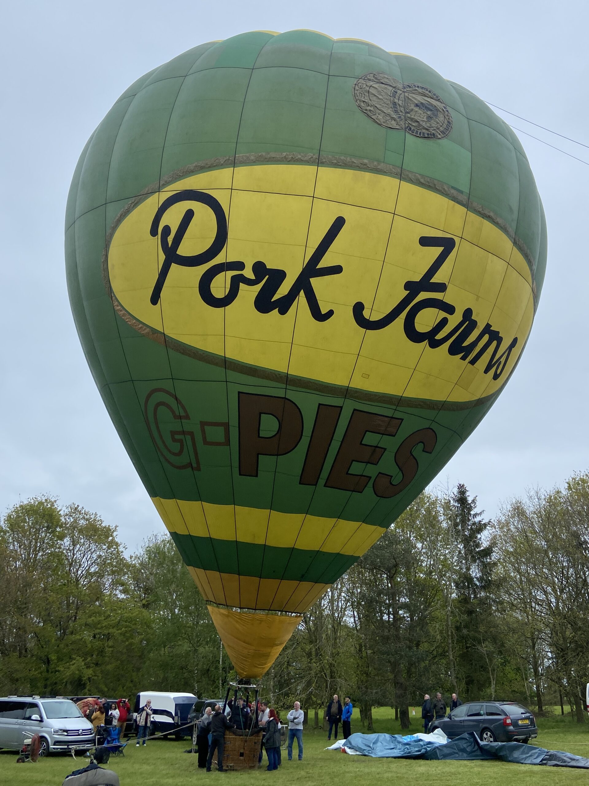 Green round balloon with 2 yellow horizontal stripes at base. 'Pork Farms' artwork in gold, black and yellow. Registration in large gold lettering underneath the artwork.