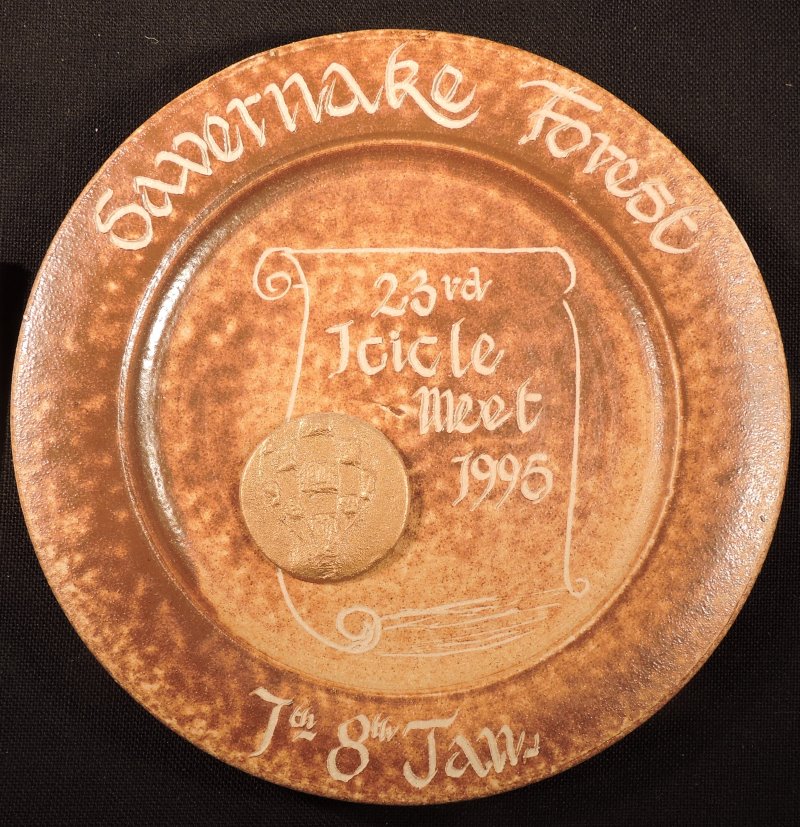 Light brown/beige mottle effect ceramic plate with event details in cream on the rim. In the centre is the outline of a scroll in cream with the words 23rd Icicle meet 1995. On the scroll is an embossed circle with an image of a balloon all in gold.