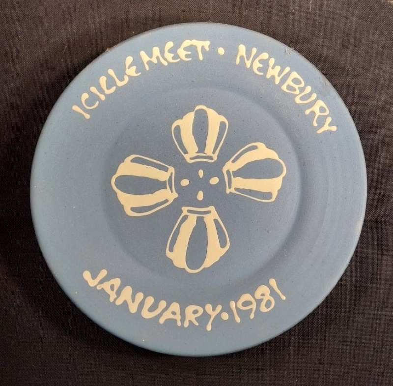 Light blue plate with event details painted in white on the rim and four white very basic balloons painted in the centre in a round to look like a flower.
