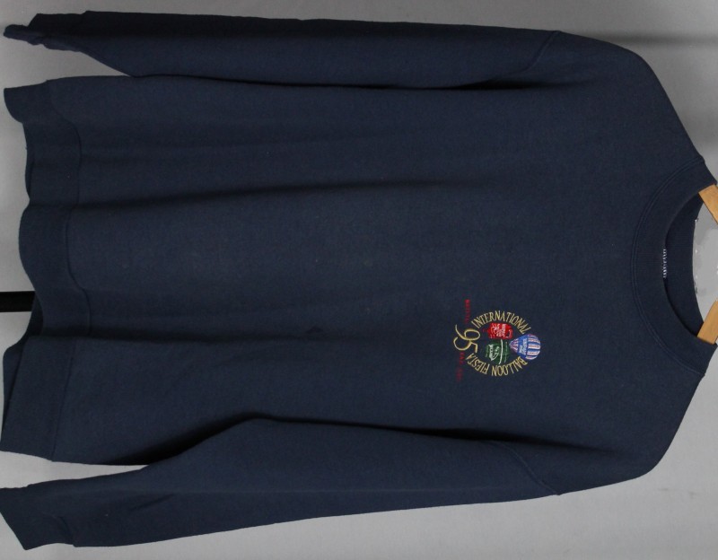Navy blue sweatshirt with event name embroidered in a circle on the left chest in gold, with the red, white and blue Unipart balloon top centre, red Unipart oil can inside the circle on the left and the round, green, Jaguar car balloon on the right.