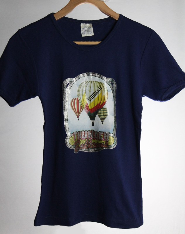 Navy blue T-shirt with stick on photo image of 3 colourful balloons in the clouds, the larger middle balloon has 'Thunder' across it. There is a silver frame to the image and the company name in silver and red on a yellow background at the base.
