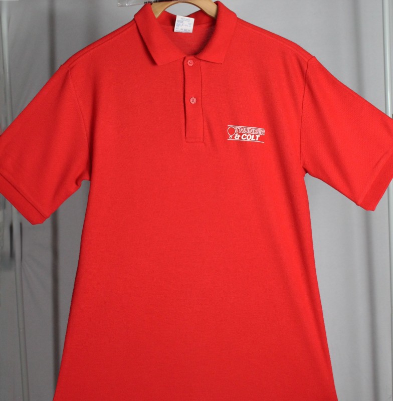 Red polo shirt with company logo in white on left chest which comprises company name with outline of a balloon to the right and white line above and below images.