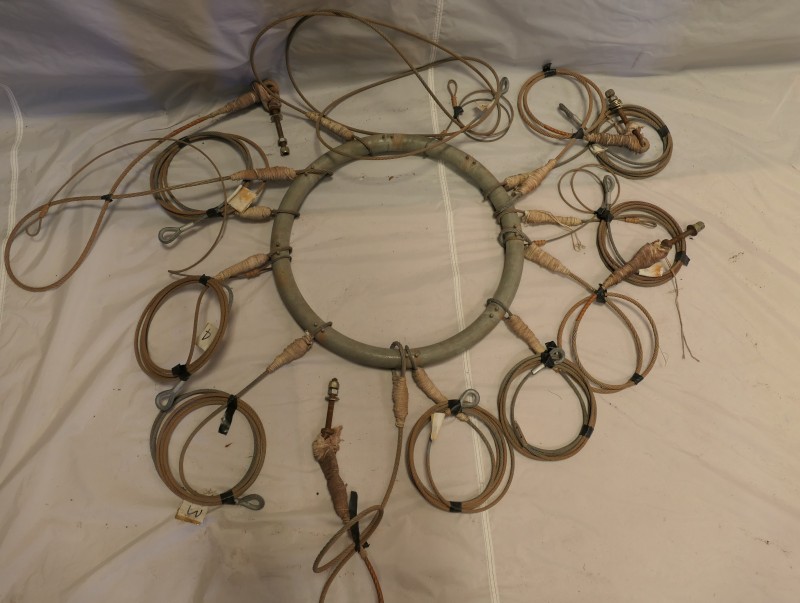 A grey metal crown ring with 15 wires connected to it. Most of the wires are looped into individual circles and fastened, to avoid wires becoming entangled in storage. 