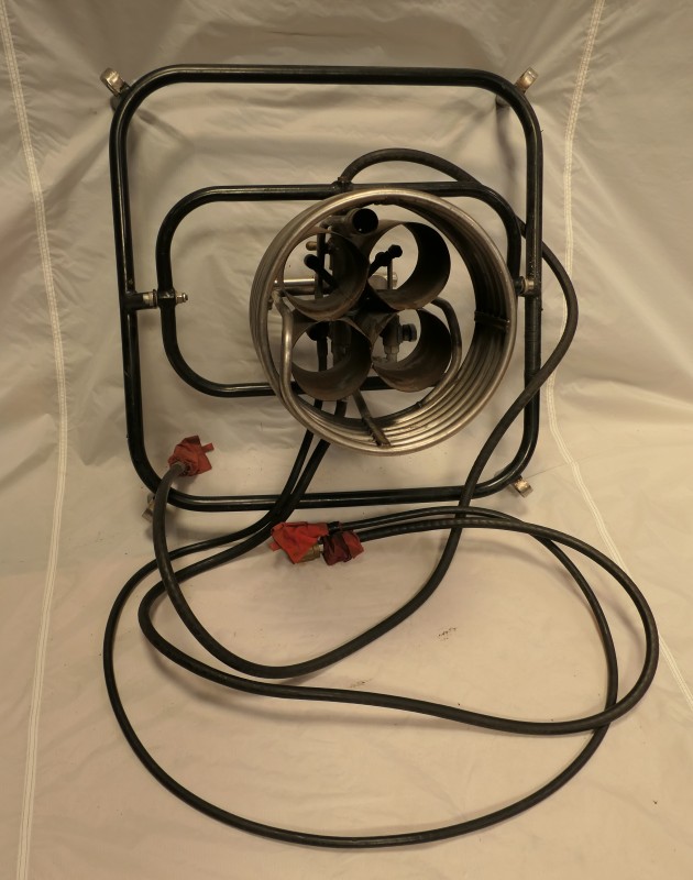 A single burner with 4 gas inlets sat in a black frame which gimbals within a larger black frame. 3 gas hoses are attached including a thinner pilot light hose.  