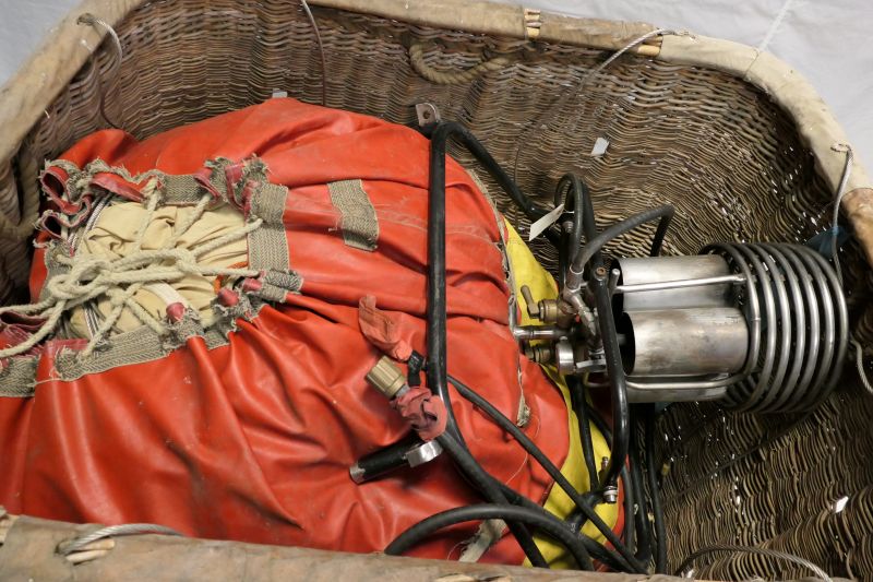 View looking into the top of the basket showing the orange and yellow envelope bag containing G-BBOX and a black framed single burner.