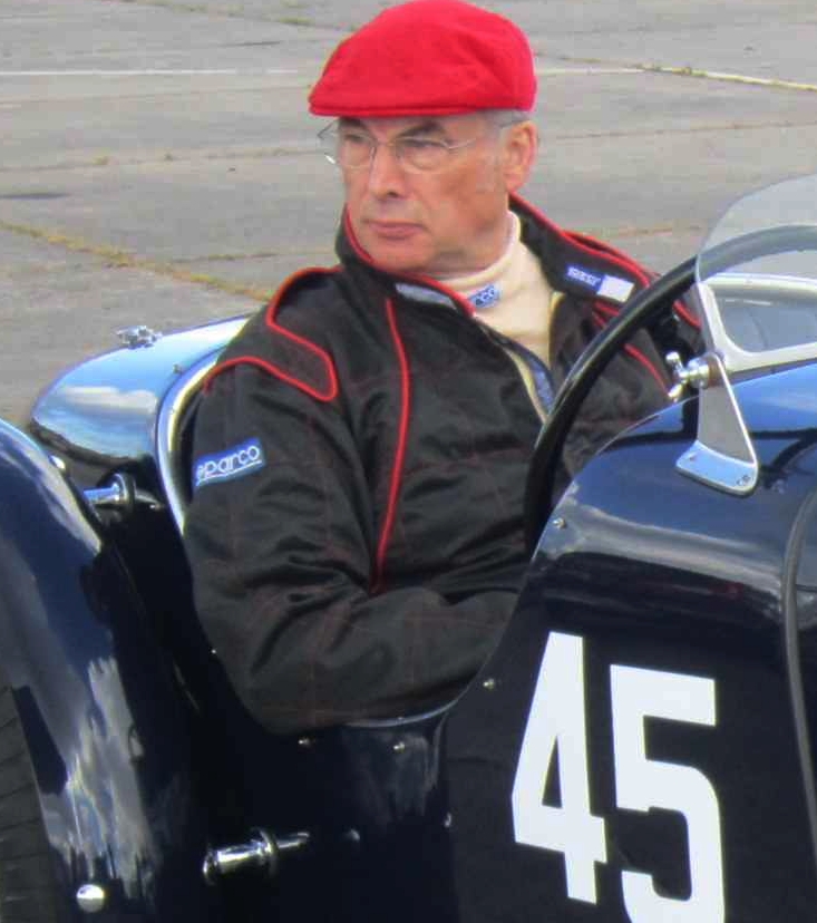 Colin Wolstenholme in a Riley car wearing a red hat