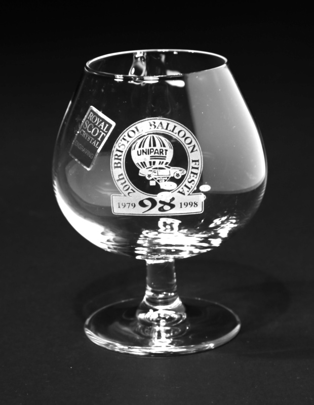 Brandy glass with engraved circle featuring the Unipart round balloon and Jaguar car balloon. Around the circle is the text '20th Bristol Balloon Fiesta' with the years 1979 - 1998 at the base of the circle. 