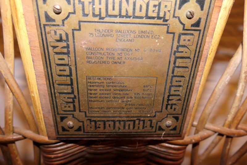 Brass basket construction plate including the balloon registration details and the restrictions in terms of operating temperature, maximum climb and descent rates, load weight, and maximum wind speed.